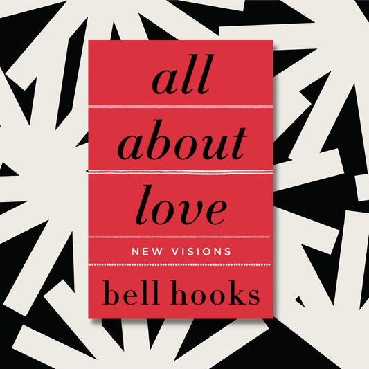 The red paperback of All About Love by bell hooks rests on a background with white lines on a black background.