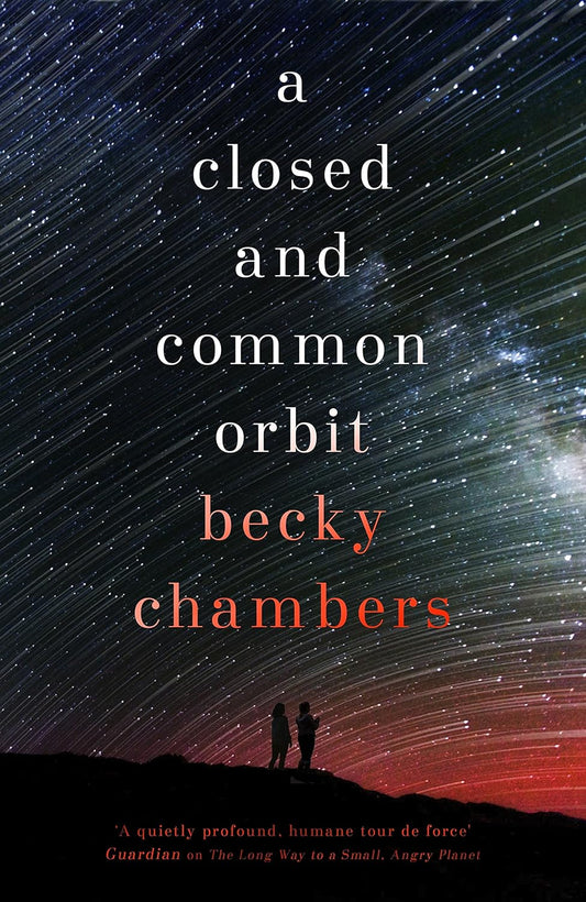 The cover for A Closed and Common Orbit shows two figures stood on a mountain top looking at billions of stars streaking across the sky, leaving their light trail in their wake.