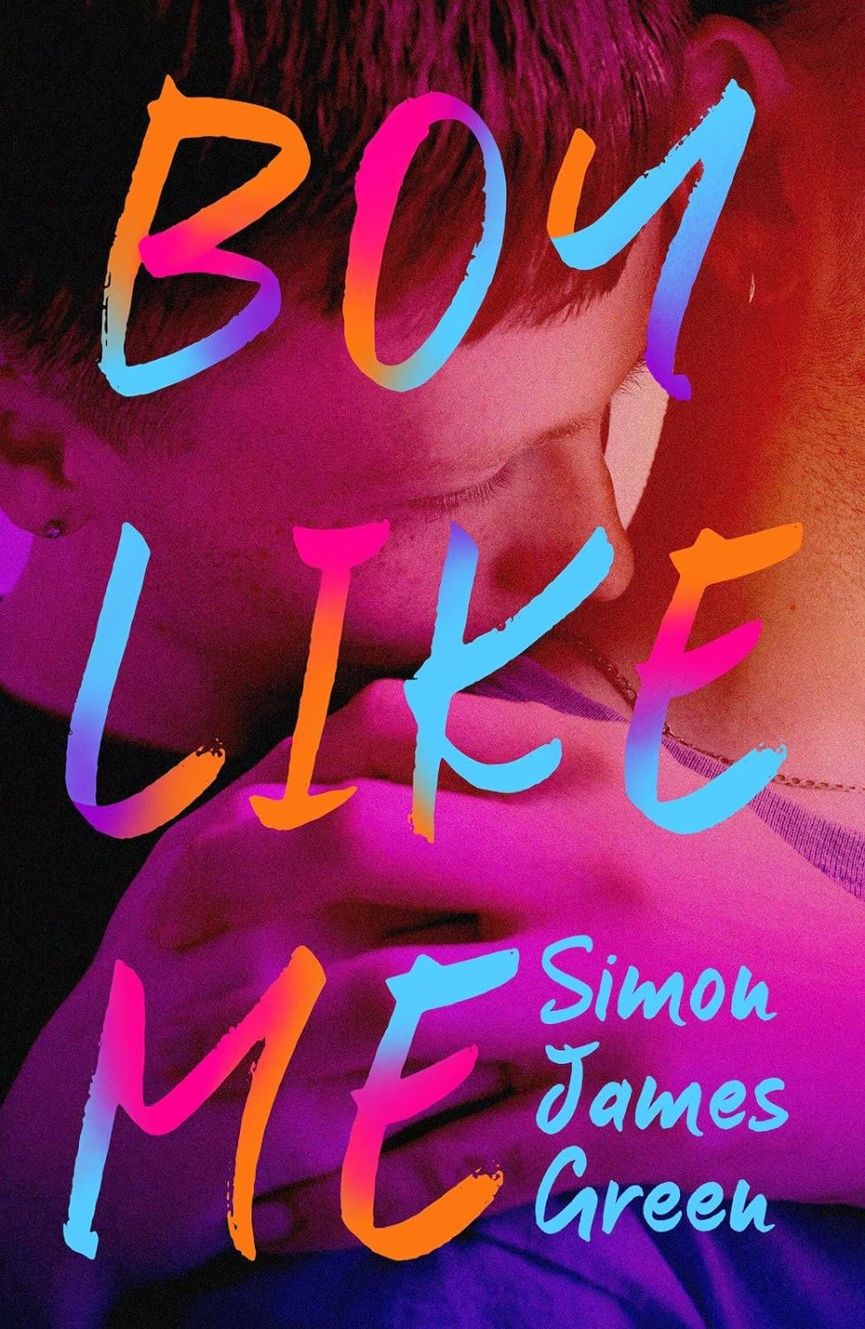 Two young white boys are on the cover for Boy Like Me. One boy stands behind the other, his hand on the other's shoulder, his head lovingly in the crook of the other boy's neck/ The cursive, handwritten font for the title and author name is in the colours orange, blue, and pink.