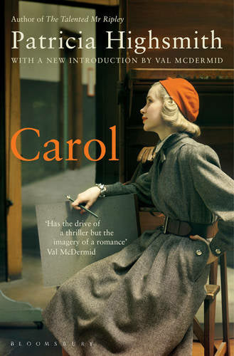 The book cover of Carol. A white lady, Carol, with blonde hair wearing a grey coat and orange hat sits on a chair.