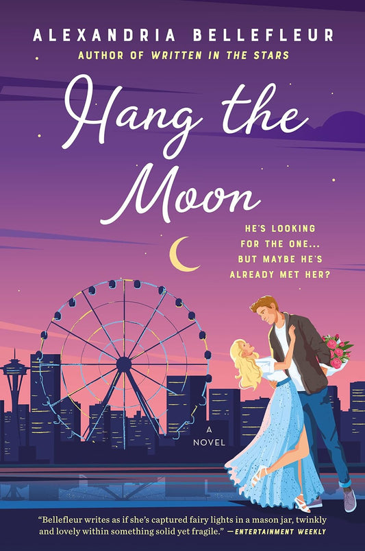 The book cover for Hang the Moon shows the Seattle skyline at dusk, a crescent moon hanging in the sky. A white man and woman embrace one another. Yellow text reads "He's looking for the one ... but maybe he's already met her?"