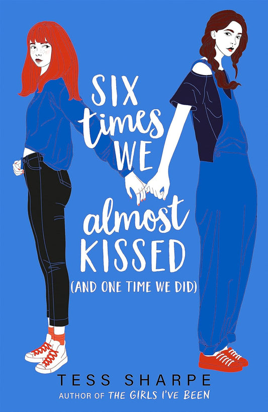The blue book cover for Six Times We Kissed and One Time We Did shows two white girls stood on opposite sides of the cover with their pinkies linked together.