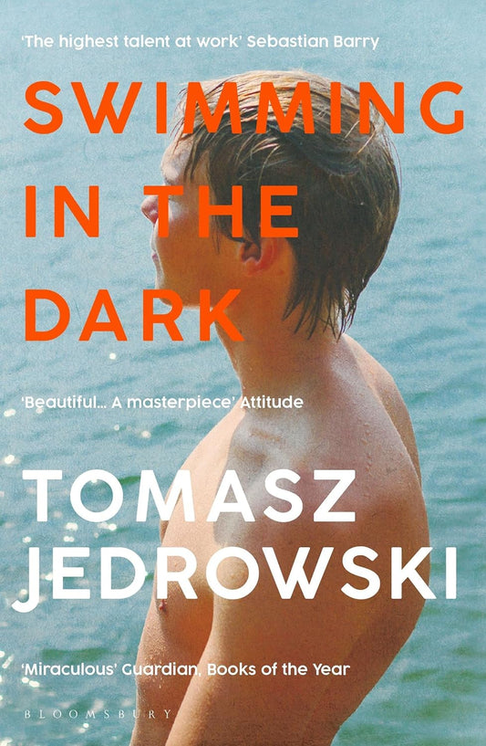 The book cover for Swimming in the Dark shows a young shirtless white man covered in speckles of water stood by the sea.