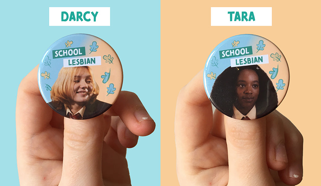 Heartstopper character Darcy and Tara and printed on their own individual badges. Darcy is a white teen girl and there is text that says “School Lesbian” on her badge. Tara is a Black teen girl and there is text that says “School Lesbian” on her badge. 